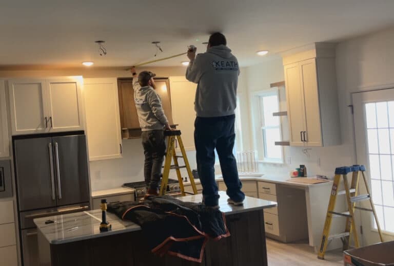 Electricians installing new lighting in a kitchen.