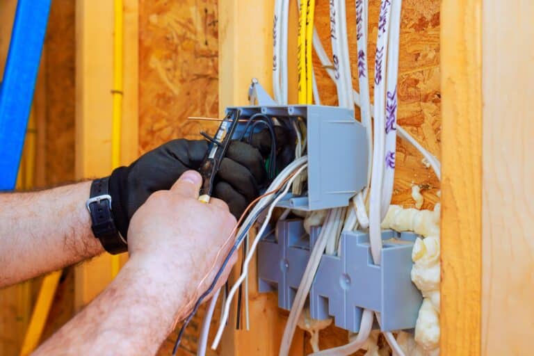 Electrician clipping wires in junction box.