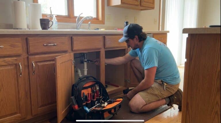 Keath HVAC plumber repairing drain under kitchen sink