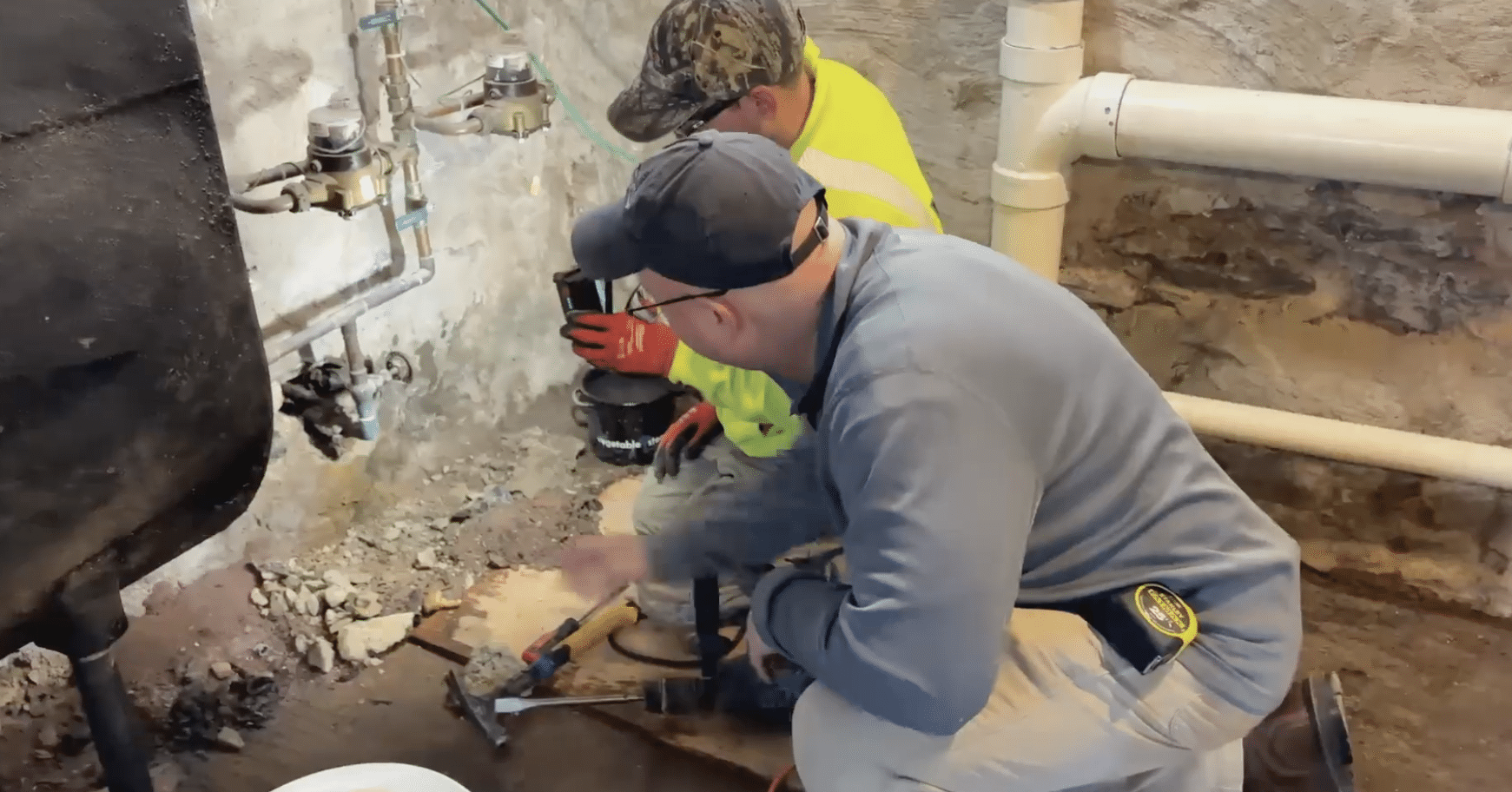 Plumbers working on water line repair in customer's basement.