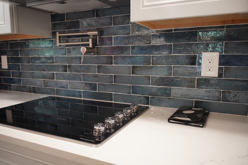 Flat-top range with blue tile backsplash and pot filler faucet.